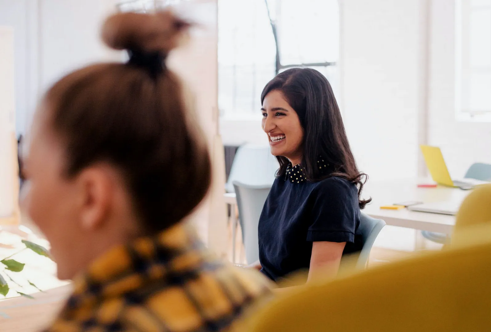 Deux femmes souriantes au bureau, effet de zoom et de profondeur