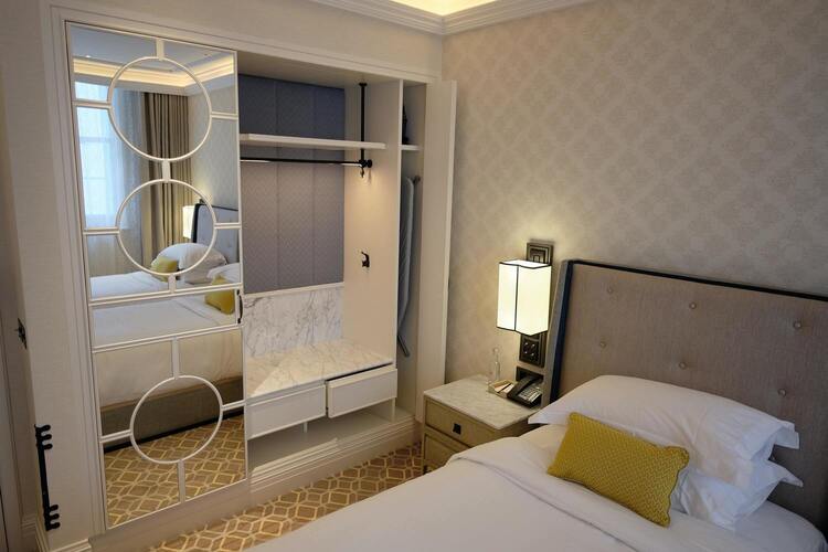 Image de la chambre d'hôtel montrant un lit double et un grand placard avec miroir